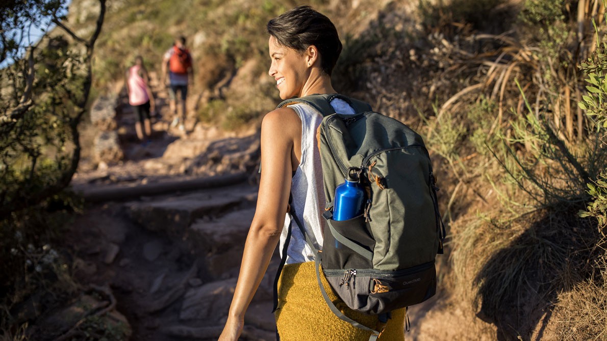 Person smiling on a sunny hiking trail